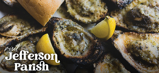 A platter of chargrilled oysters is served with lemon wedges and French bread.