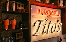 A neon Love, Tito's sign next to shelves of branded tumblers at the Love, Tito's retail store in Austin,
