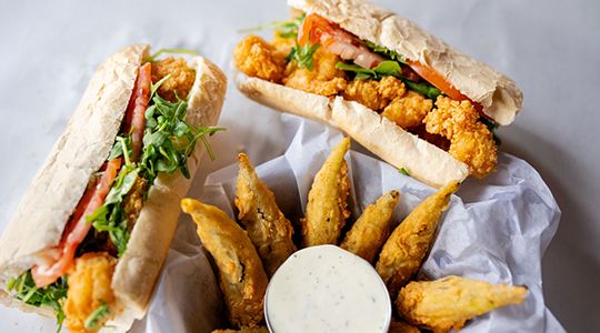 An older couple sits at a diner booth eating breakfast with coffee and juice.