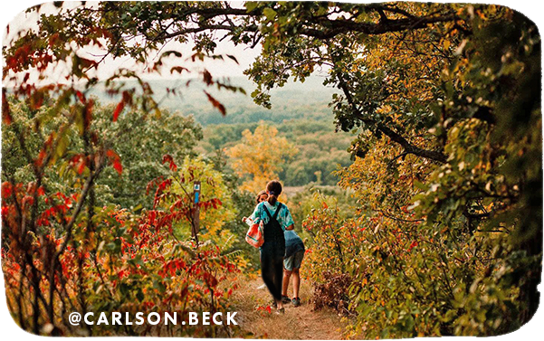 Kids walking on a trail surrounded by trees with red, green and yellow leaves, with overlay text that reads: @carlson.beck