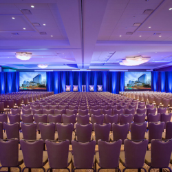 Meeting space with a stage, royal blue curtains and rows of chairs inside the JW Marriott Austin