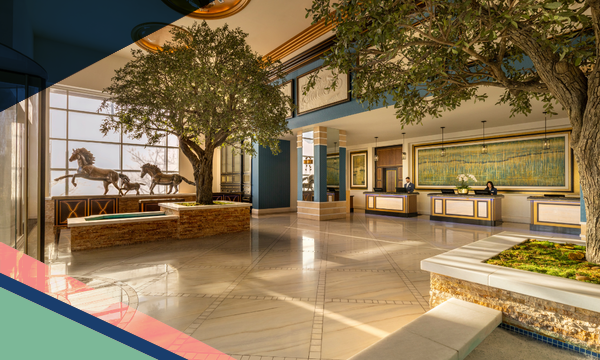Interior view of the Fairmont Austin lobby with benches, trees, reservation desks and horse statues