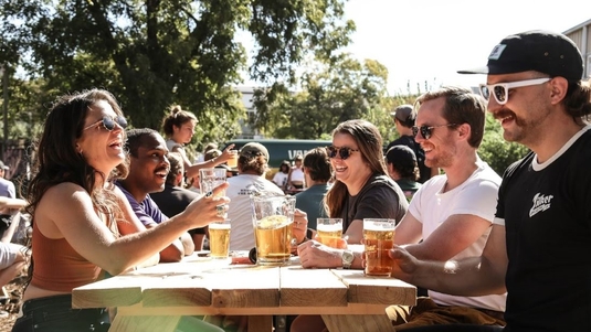 A group of friends sip beers at an outdoor picnic table at Zilker Brewing Co. in Austin, Texas
