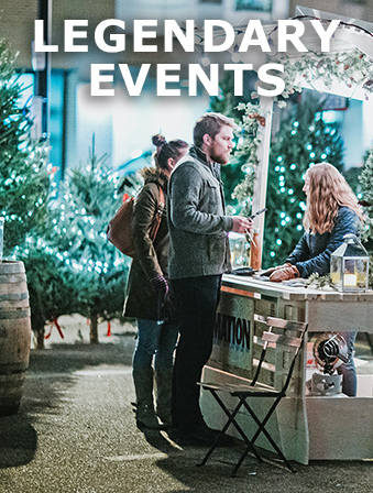 Man and a woman shopping at an outdoor booth with Christmas trees in the background, with overlay text that reads: Legendary Events