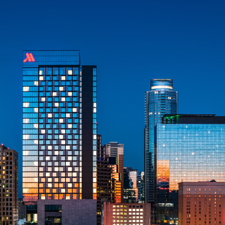 An evening cityscape view featuring lights glowing from windows of the Austin Marriott Downtown 