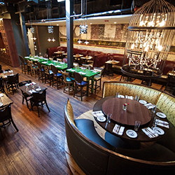 The wood-floor dining room with tables, chairs and booths inside Swift's Attic in Austin, Texas