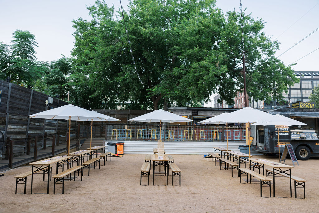 Alt text: Rows of picnic tables shaded by white umbrellas at the Historic Scoot Inn in Austin, Texas