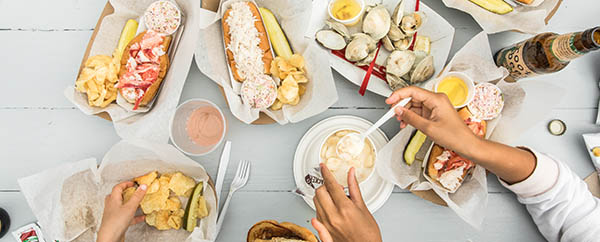 Aerial view of a white picnic table with lobster, clams and onion rings 