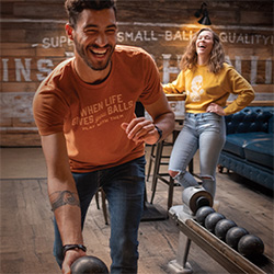 A man with a bowling ball in hand is ready to roll it down the lane while a woman behind him laughs at Pins Mechanical Co. in Austin, Texas