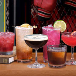 Six specialty cocktails lined up on a bar at Pins Mechanical Co. in Austin, Texas