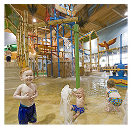 Three young children playing at an indoor water park