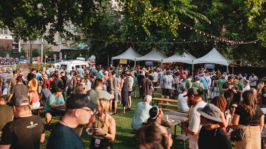 Attendees mingle under shady trees and tents at the outdoor Hot Luck food festival in Austin