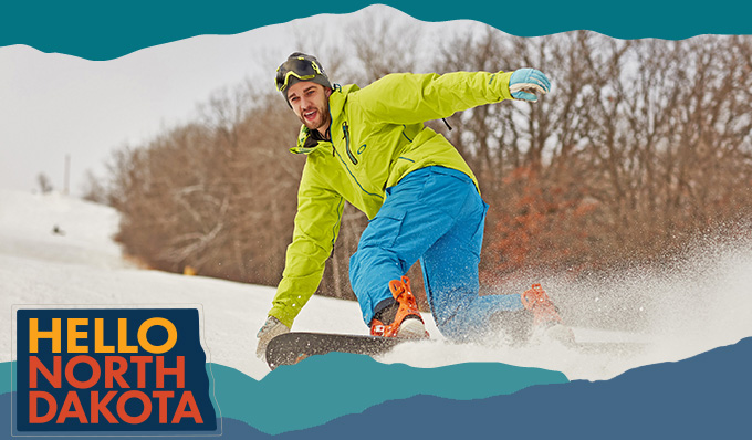 Man wearing a bright green coat and blue pants riding a snowboard through snow, with overlay text that reads: Hello North Dakota