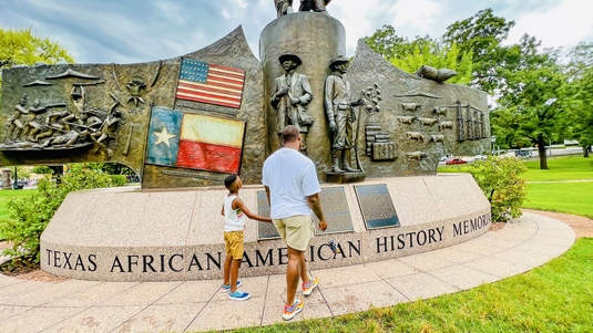 A man and boy walk beside the Texas African American History Memorial in Austin, Texas