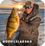 Man proudly holding up a caught fish in front of a frozen lake at sunset, with overlay text that reads: @devilslakend