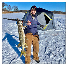 Man standing on a frozen lake holding a spear with a fish on it