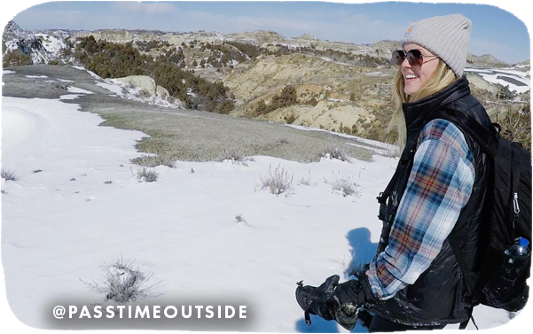 Woman hiking in a snowy landscape with rocky hills in the background, with overlay text that reads: @passtimeoutside