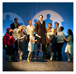 Cast members on the stage of a theater with a spotlight on them in North Dakota