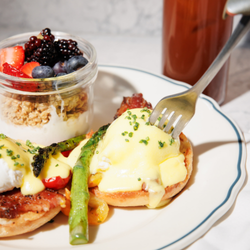 Eggs Benedict served for brunch with asparagus and a side of granola and fruit at Skipjack Oyster in Austin 