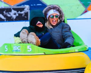 Woman and a child wearing winter clothes and riding on an ice bumper car