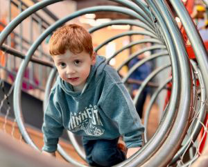 Young boy climbing through metal play structure
