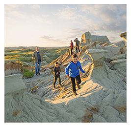 A family with young boys walking through rock formations with grassy hills in the background