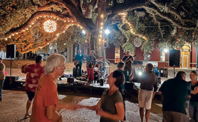 A group of people laughing and dancing under twinkling lights.