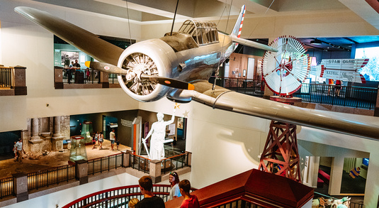 An airplane hangs from the ceiling above exhibits in the Bullock Texas State History Museum in Austin, Texas