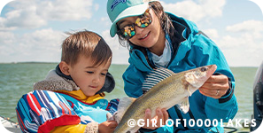 Two young children on a boat inspecting a caught fish, with overlay text that reads: @girlof10000lakes
