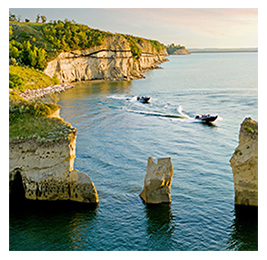 View from a distance of two speedboats on a lake framed by rocky cliffs