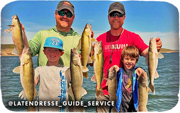 Two men and two young boys holding up several caught fish with water in the background, with overlay text that reads: @latendresse_guide_service