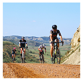 Group of people riding bikes on a gravel path with green hills in the background