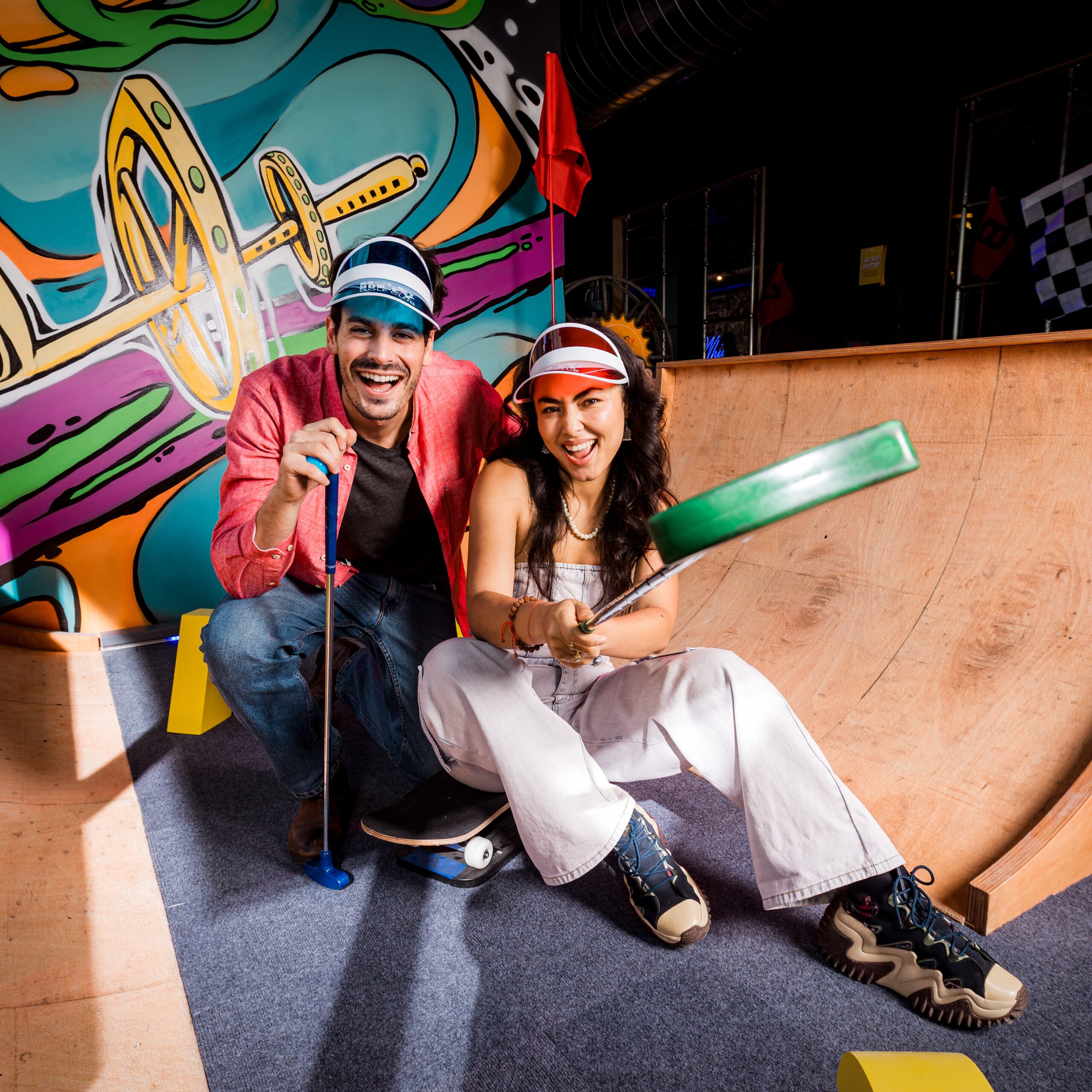 Two people pose at a hole during a game of indoor mini golf at Holey Moley in Austin, Texas