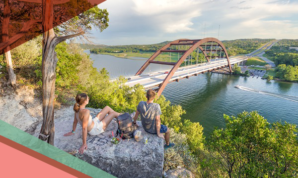 Two people sit on a large rock along a hiking trail at the Pennybacker Bridge Overlook near Lake Austin in Texas