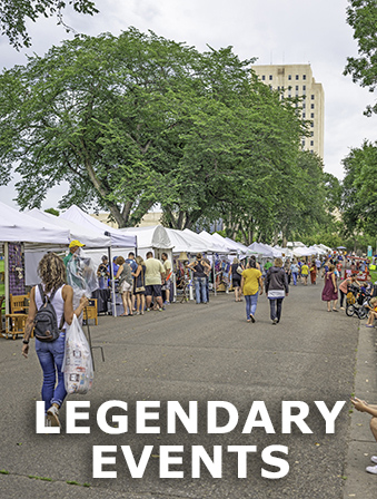 View of a street fair with people walking around outside and looking at vendors under white tents, with overlay text that reads: Legendary Events
