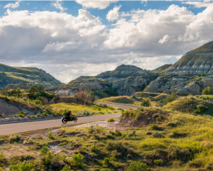 View of a motorcycle on a winding road in the distance, surrounded by scenery of unique rock formations