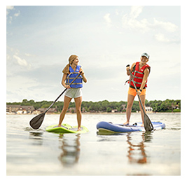 Two women stand-up paddleboarding on a lake