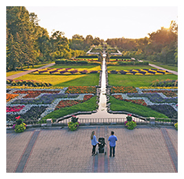 Aerial view of a family standing on a brick terrace looking out to a colorful garden