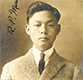 A headshot of an Asian American in a suit and tie gazing into the camera.