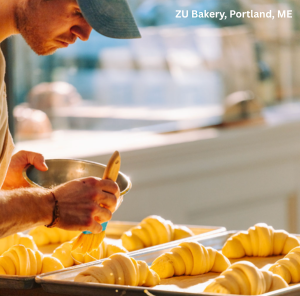 Baker buttering croissants just before placing them in the oven