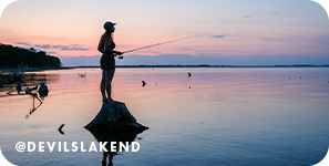 Silhouette of a woman standing on a rock fishing with a pink sunset in the background, with overlay text that reads: @devilslakend