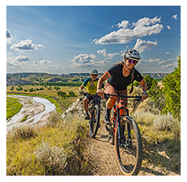 Two people riding mountain bikes in scenic terrain of North Dakota