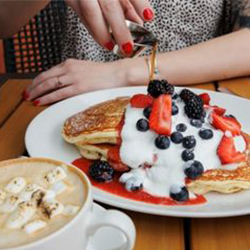 A plate of pancakes topped with berries and whipped cream served at Caroline at Aloft Austin Downtown in Austin, Texas