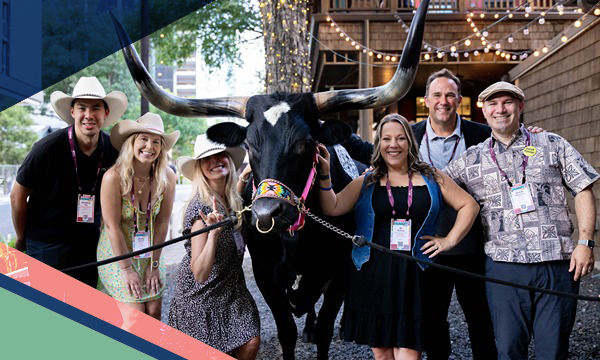 Six event attendees stand next to a Texas Longhorn on a city sidewalk outside a venue in Austin, Texas 
