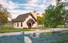 Grave markers in the foreground of the historic Oakwood Cemetery Chapel in Austin, Texas
