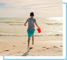 boy running with sand bucket on siesta beach