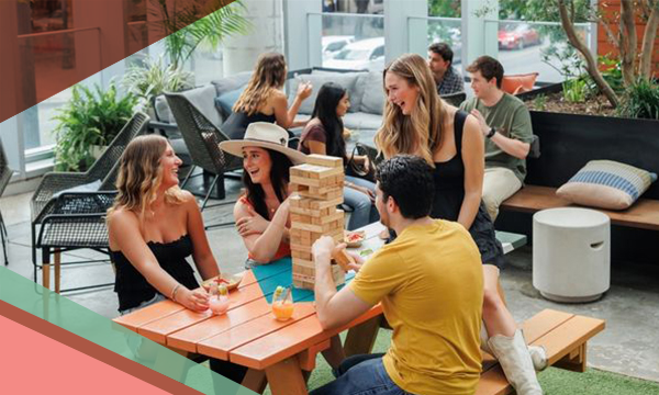 Groups of people socialize at picnic tables outdoors at Upstairs at Caroline, a rooftop bar and restaurant in Austin, Texas