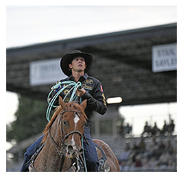 Man riding a brown horse and holding a lasso at a rodeo in North Dakota