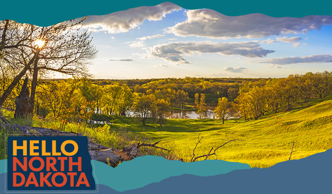 Scenic landscape of a hilly valley with orange and yellow trees of fall in the distance, with overlay text that reads: Hello North Dakota