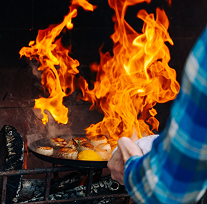 A chef cooking scallops on an open flame 